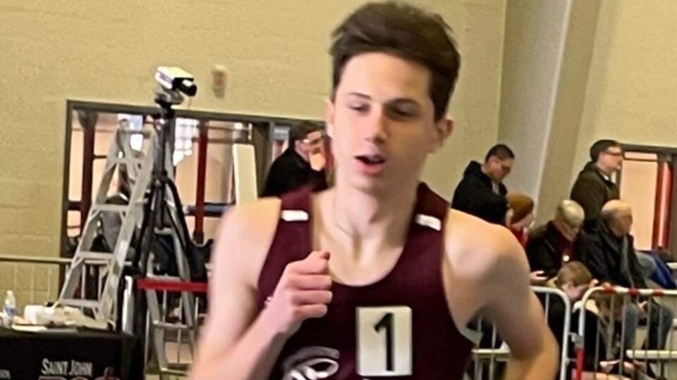 coureur portant le dossard 402 en action sur la piste d'athlétisme intérieur