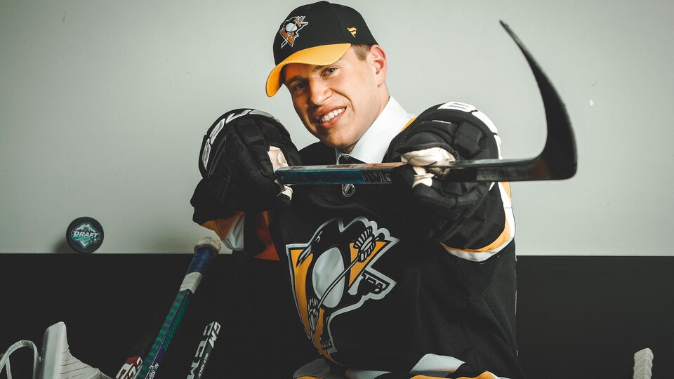 Il prend la pose avec un bâton de hockey.