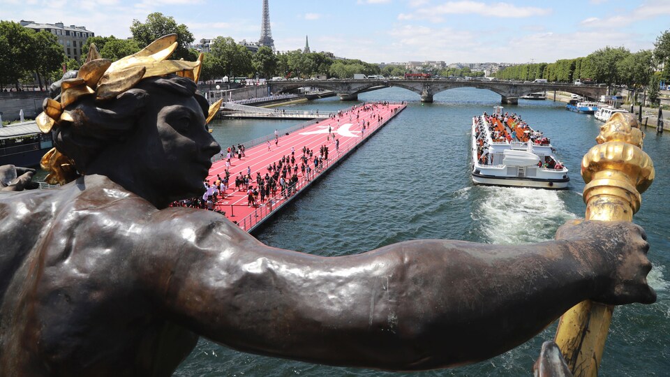 Une piste d'athlétisme est installée sur la Seine, non loin d'un bateau qui se dirige vers un pont.