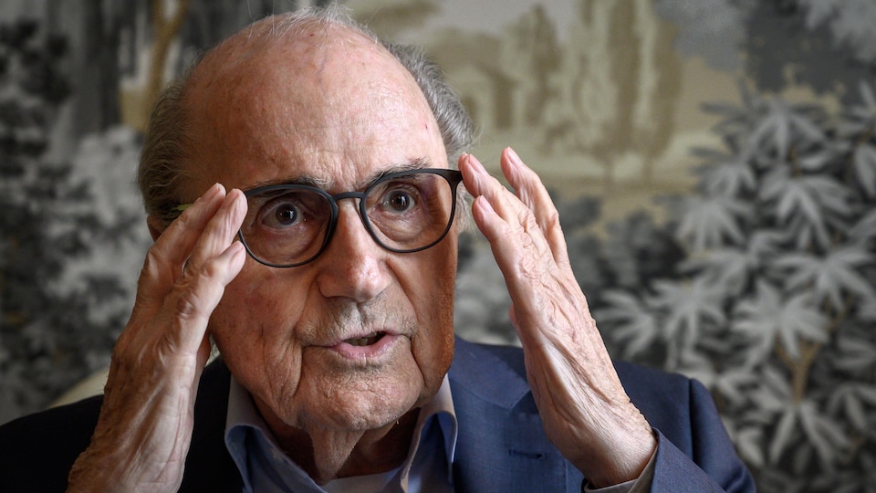 Sepp Blatter place ses lunettes avec ses deux mains.