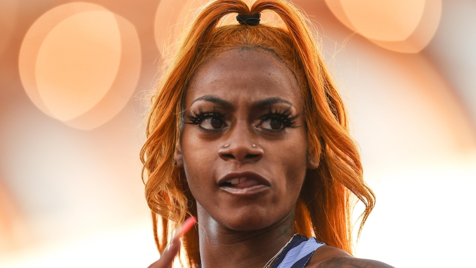 La femme à la chevelure orange regarde l'action, l'air dubitatif.