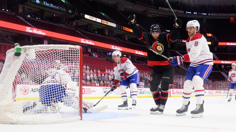 Un joueur de hockey célèbre, bras dans les airs, le premier but de sa carrière.