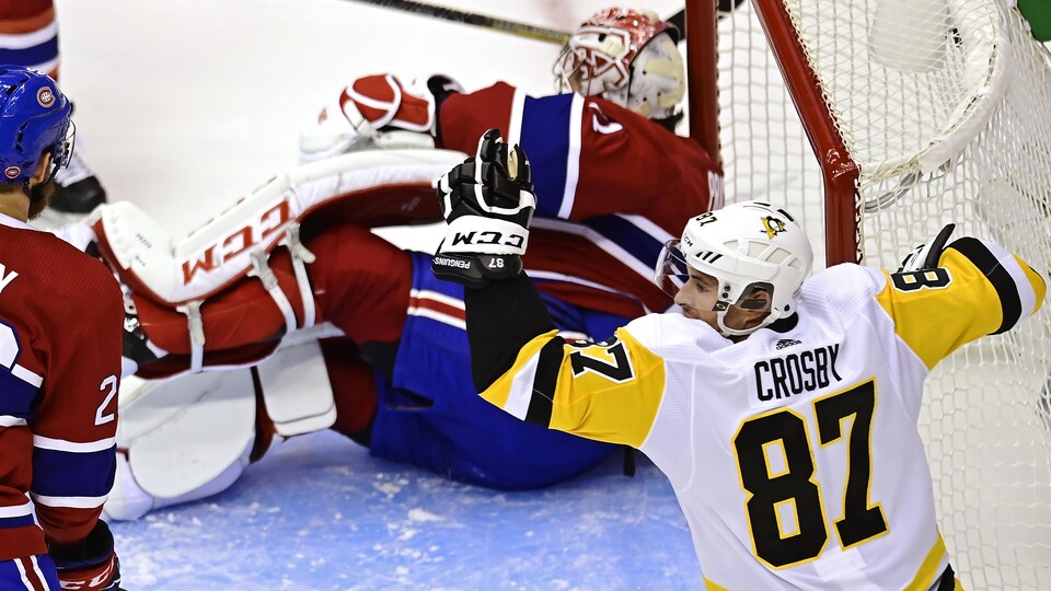 Il lève les bras dans les airs tandis que Carey Price est assis sur la glace.