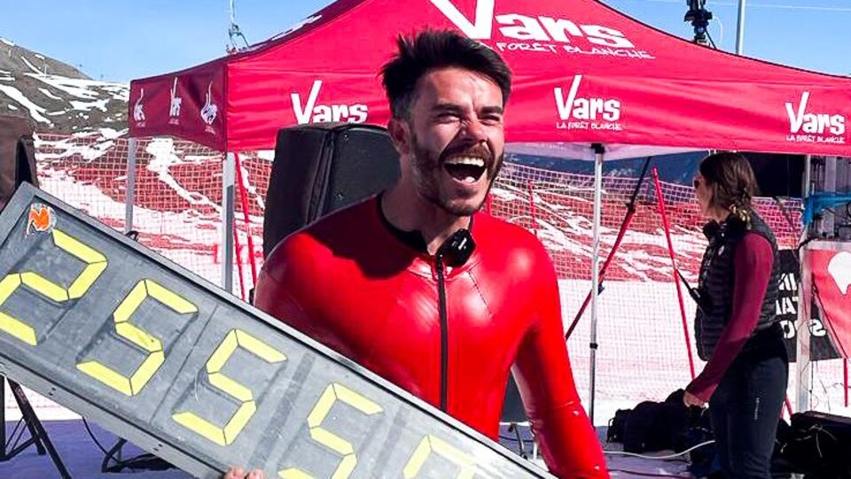 Un homme tient un panneau avec l'indication 255,5.