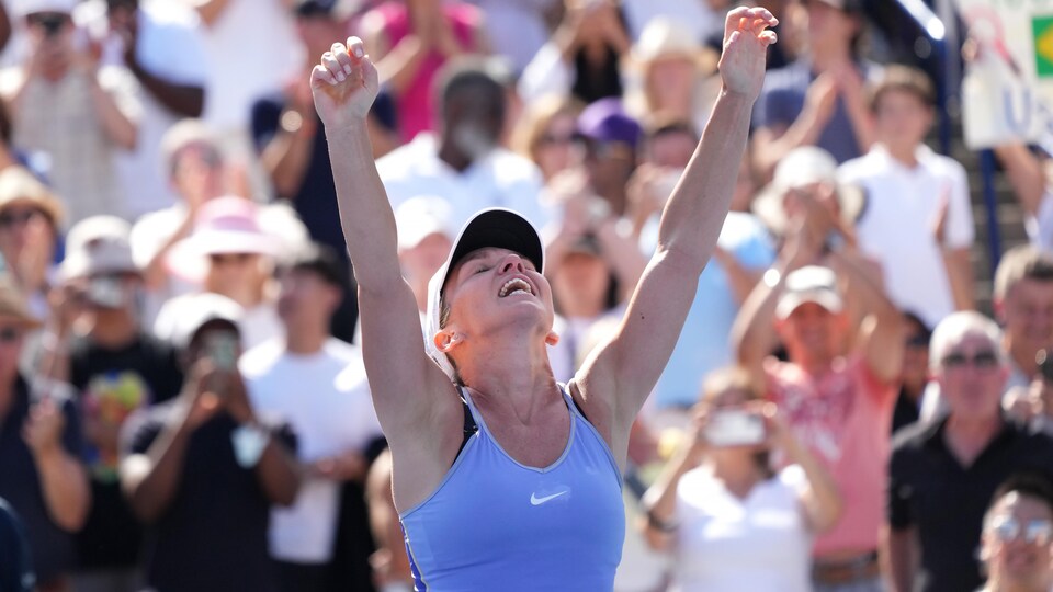 Une joueuse de tennis lève ses bras en l'air après avoir remporté un tournoi.