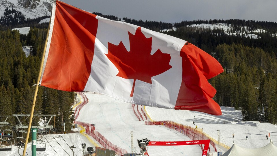 Un drapeau canadien flotte devant une piste de ski.