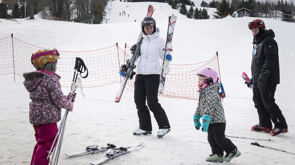 De jeunes enfants et leurs parents retirent leurs skis au terme d'une belle journée.