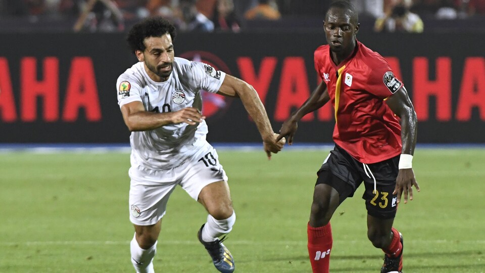 L'Ougandais Micheal Azira (à droite) tente de protéger le ballon devant l'Égyptien Mohamed Salah.