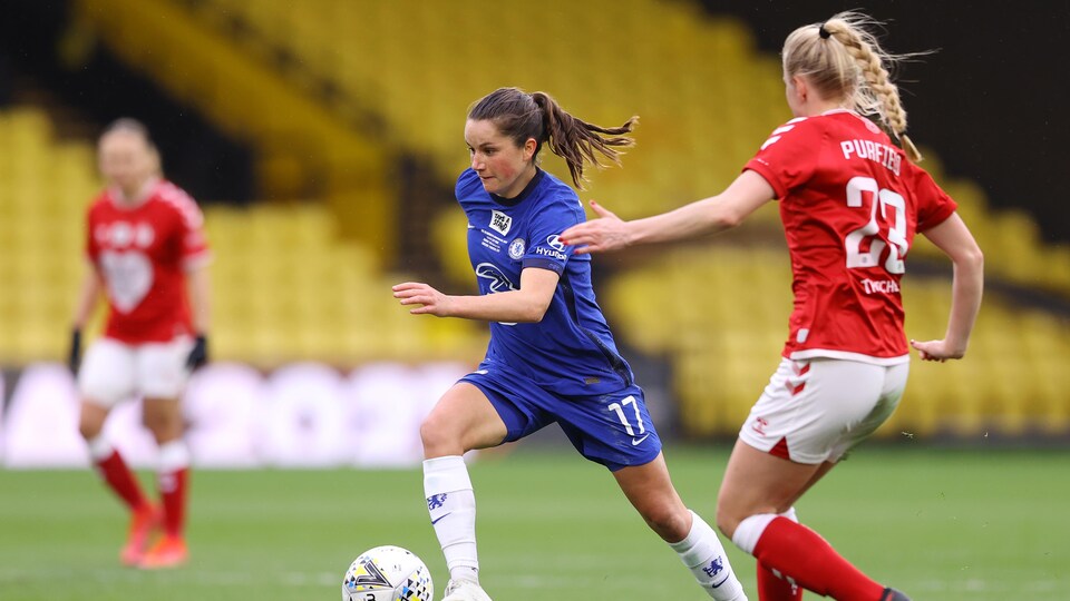 Elle court avec le ballon devant une adversaire.