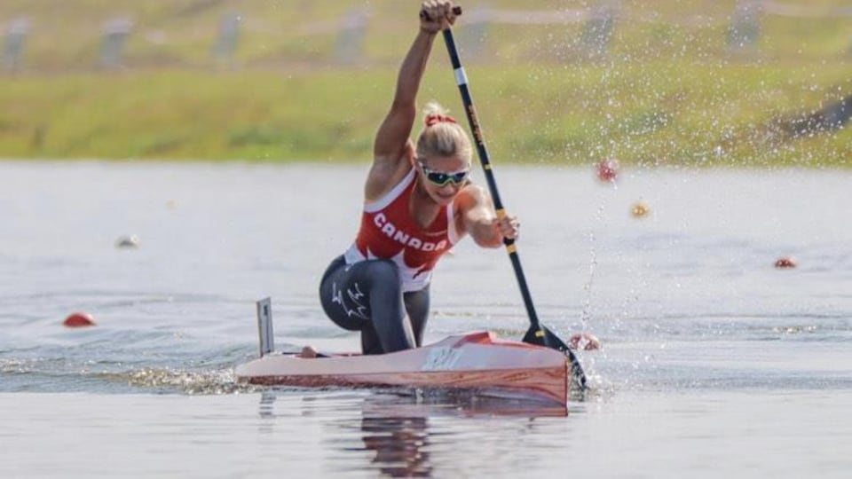 Une jeune femme rame en canoë lors d'une compétition.