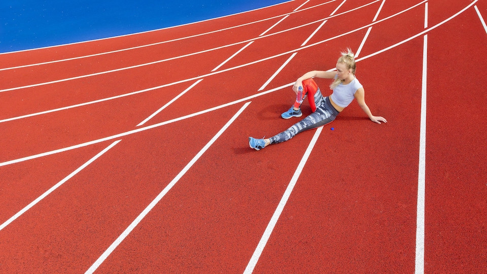 Une femme se repose sur une piste de course après avoir couru.