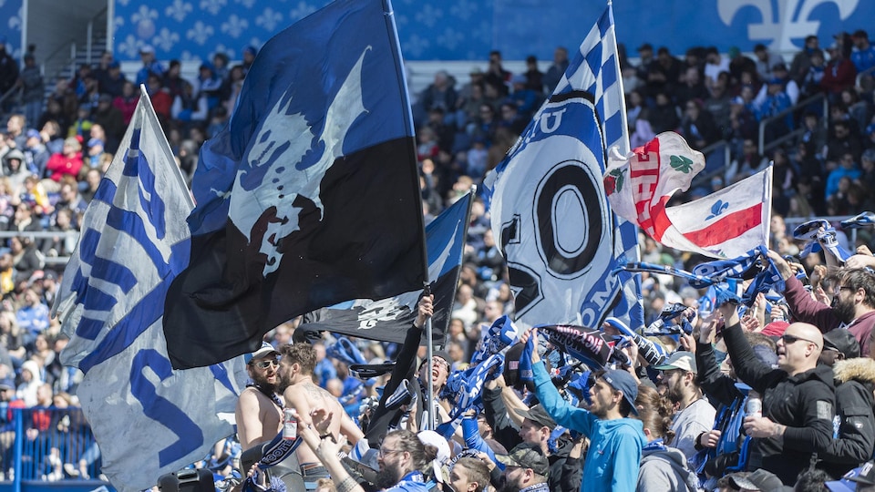 Des partisans du CF Montréal brandissent des drapeaux dans les estrades du stade Saputo.