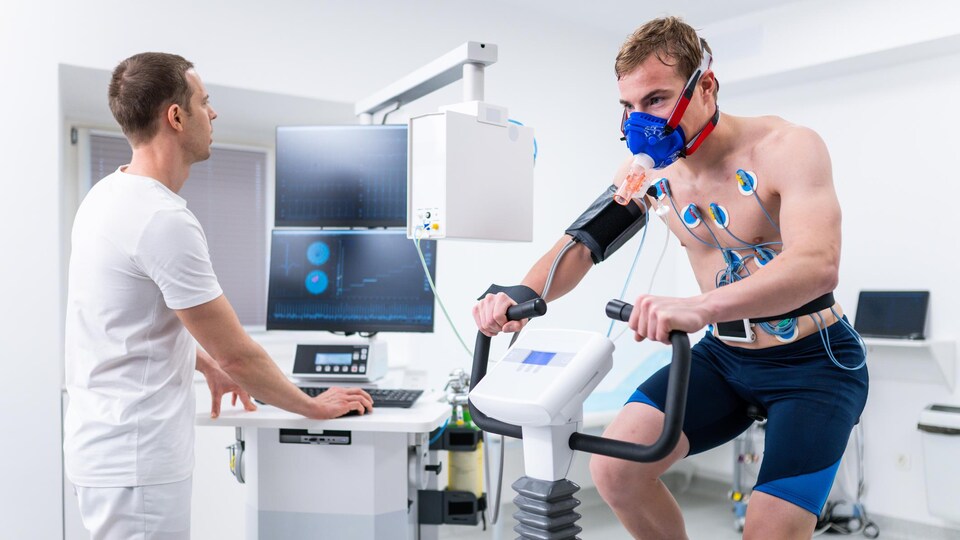 A man pedaled on a stationary bicycle;  it is attached to a monitor.
