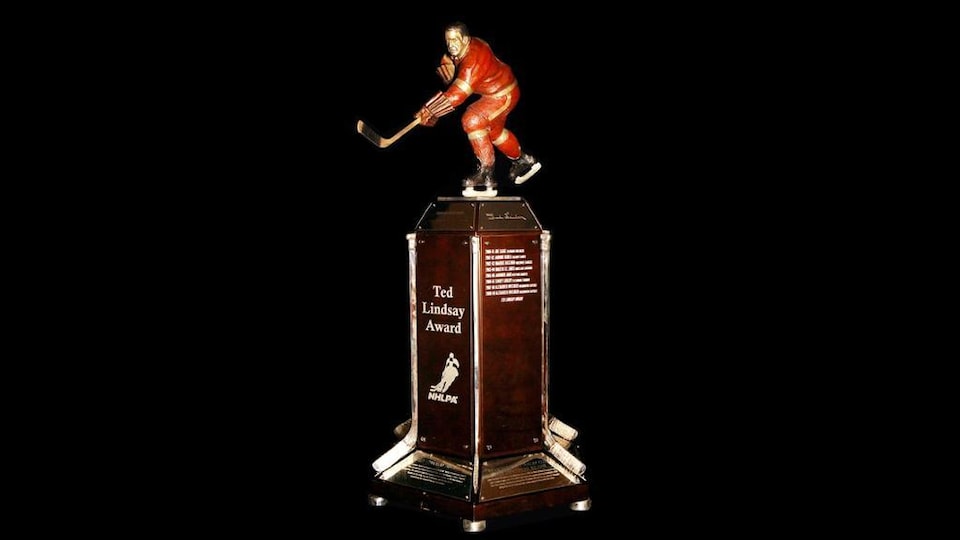 Un trophée montrant un socle rectangulaire debout surmonté d'une statuette d'un joueur de hockey.