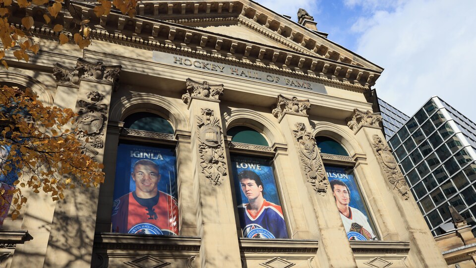 Des affiches de joueurs de hockey dans les fenêtres s'un vieil édifice. 