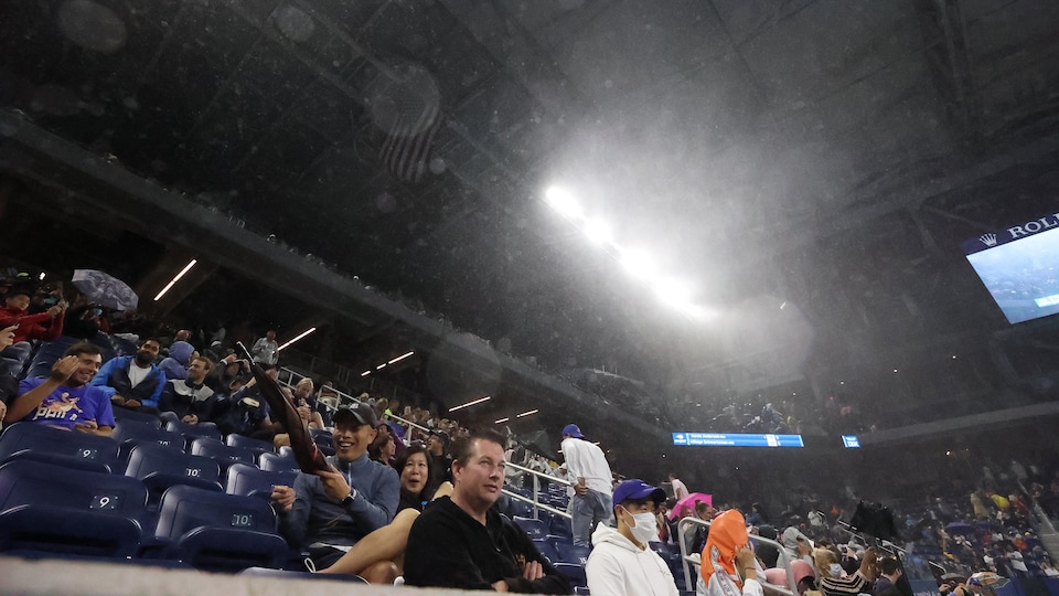 Des spectateurs sortent leurs parapluies dans les tribunes.