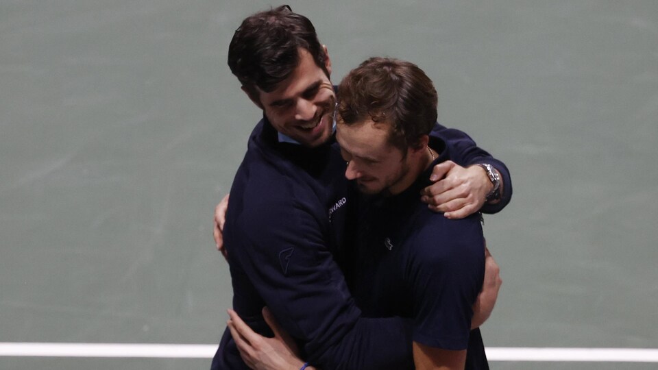 Deux joueurs de tennis s'enlacent après leur victoire.