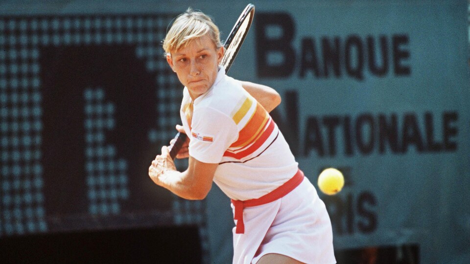 A tennis player prepares a backhand shot.
