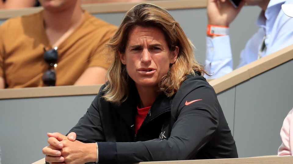 Une femme avec les yeux plissés regarde attentivement un match de tennis.