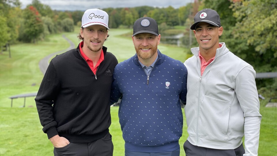 Trois hockeyeurs posent sur un terrain de golf.