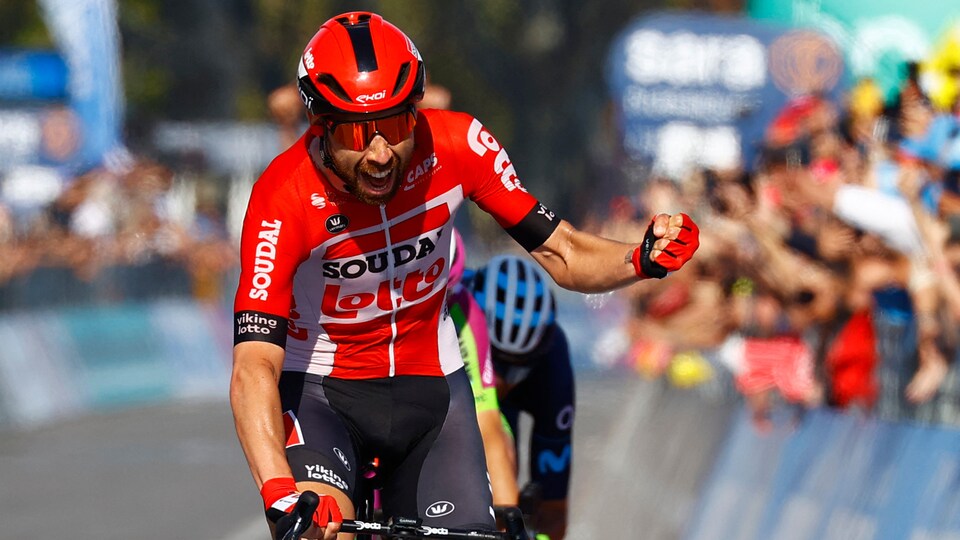 Le cycliste belge, en rouge, fait un poing pour célébrer sa victoire au fil d'arrivée. 