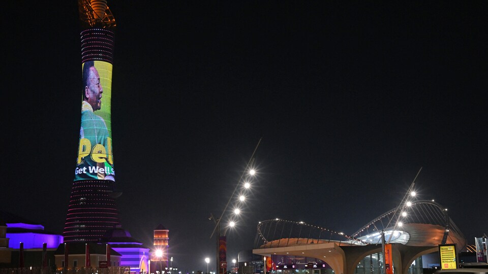 Une tour dans une ville avec la projection de l'image du joueur de soccer Pelé, la nuit.