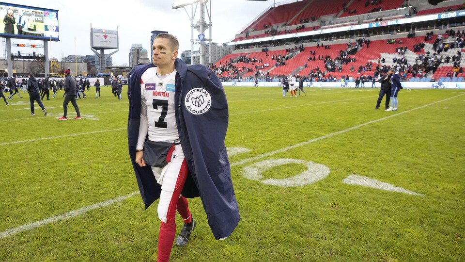 Le quart Trevor Harris se dirige vers les lignes de côté vêtu d'une grande cape aux couleurs des Alouettes de Montréal.