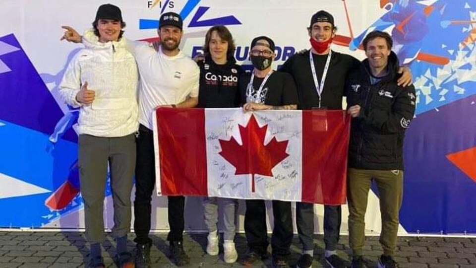 Des athlètes et des entraîneurs prennent une photo avec un drapeau du Canada.