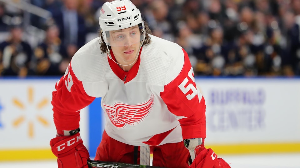 Le joueur de hockey appuie son bâton sur ses cuisses, en attendant une mise au jeu.