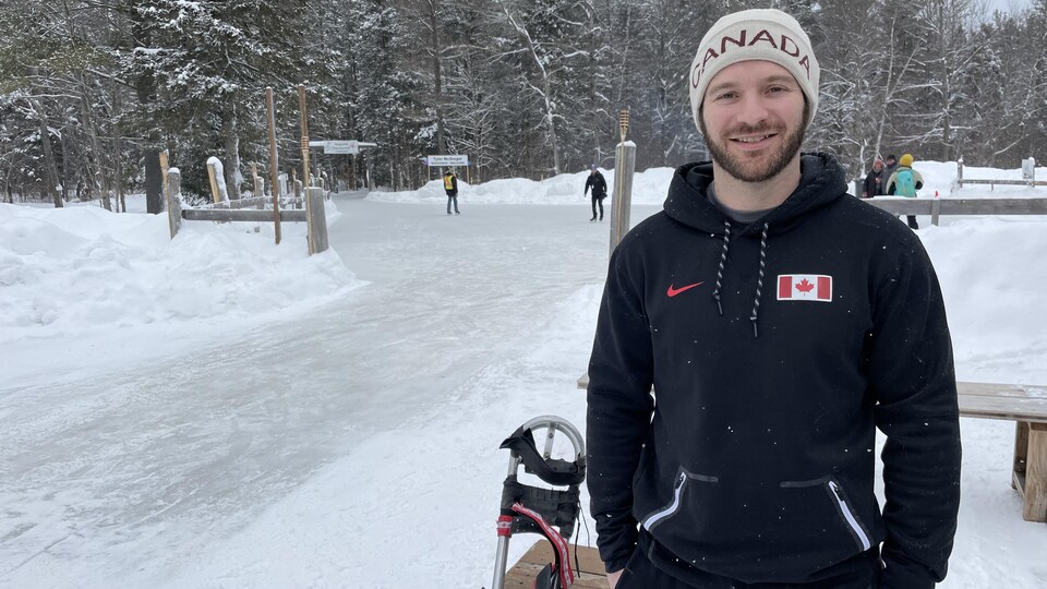 Un homme prend la pose devant une patinoire.