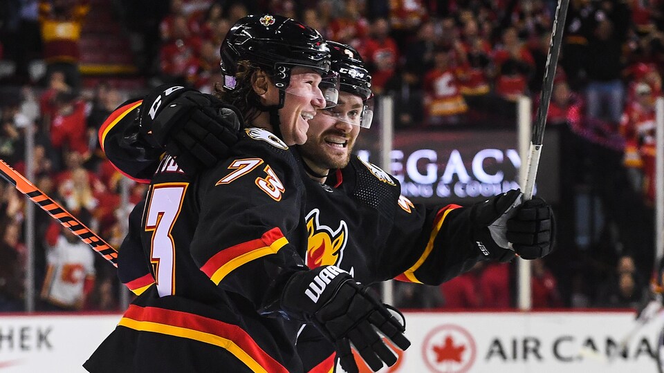 Deux joueurs de hockey sourient et s'enlacent.