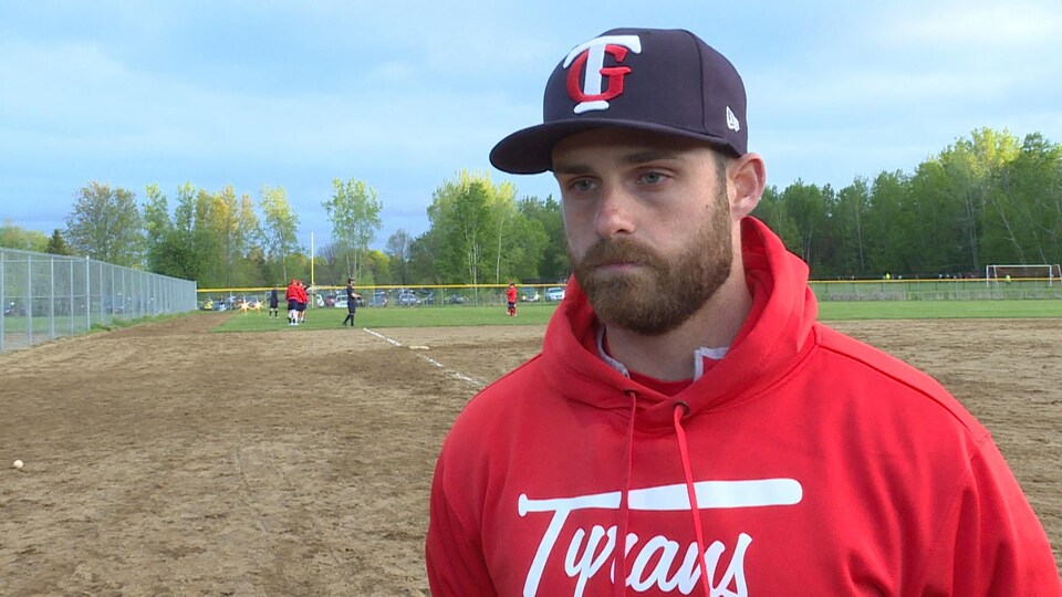 Un entraîneur de baseball s'adresse à un journaliste de Radio-Canada à la caméra.