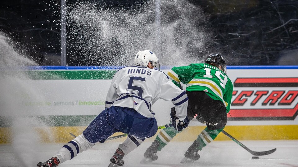 Deux joueurs de hockey freinent pendant un match et soulève un énorme nuage de neige.