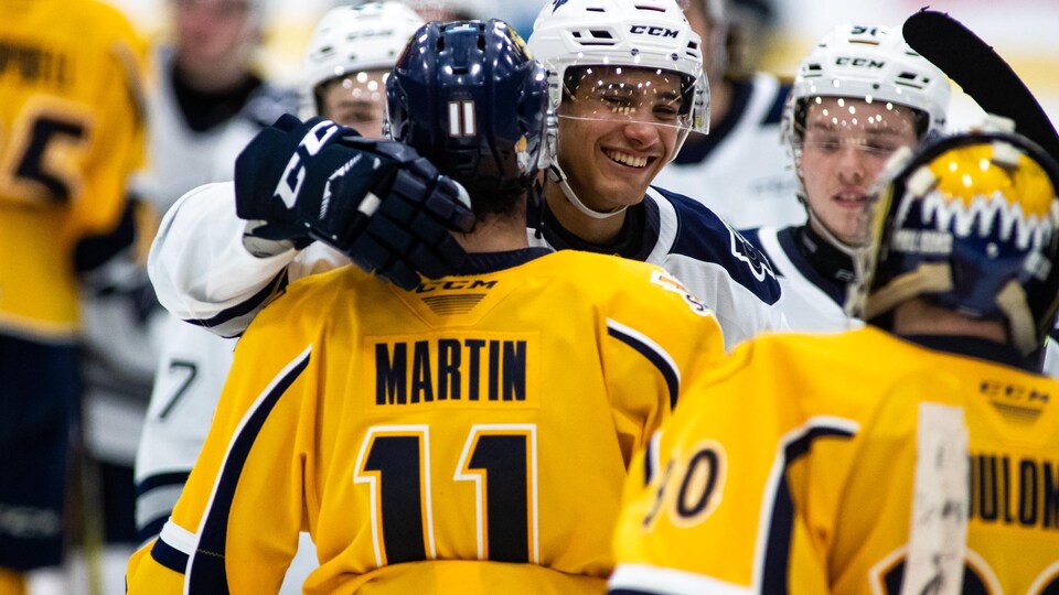 Deux joueurs de hockey se font l'accolade pendant la traditionnelle poignée après un match.