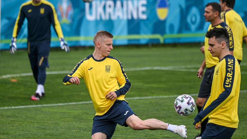Un joueur de l'Ukraine dribble avec le ballon devant un panneau sur lequel il est écrit Ukraine.