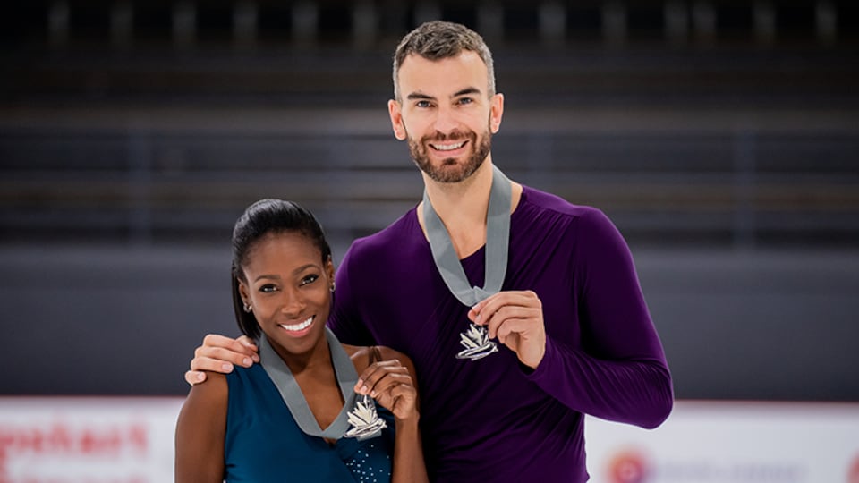 Les deux athlètes tiennent fièrement leur médaille en souriant.