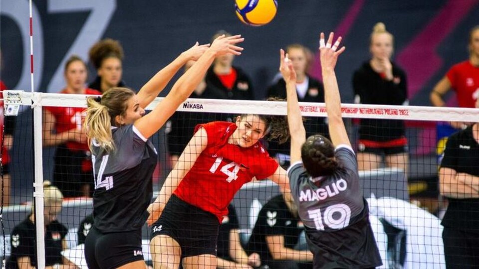 Deux joueuses sautent près du filet et bloquent le ballon.