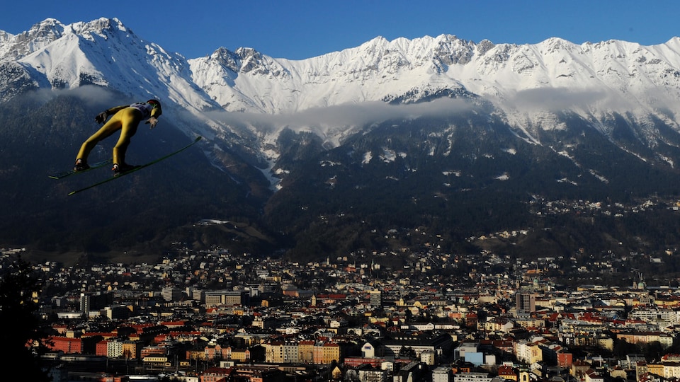Un sauteur à ski plane au-dessus de la ville d'Innsbruck, en Autriche.