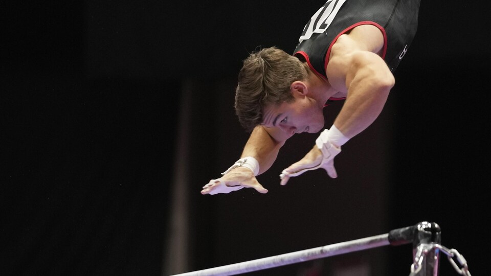 Le gymnaste William Émard s'apprête à agripper une barre horizontale.