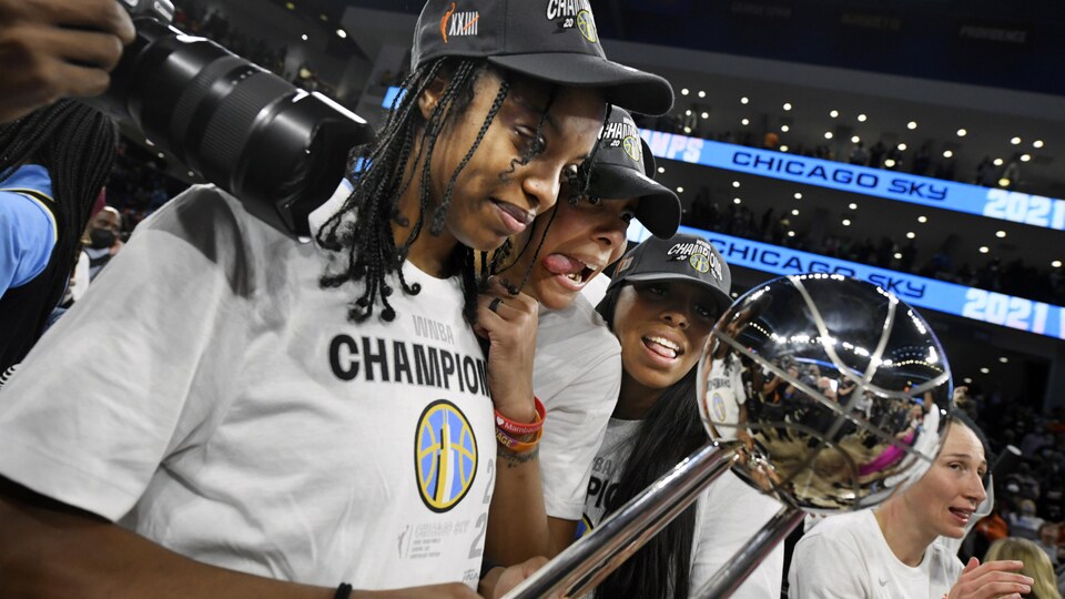 Des basketteuses regardent un trophée.