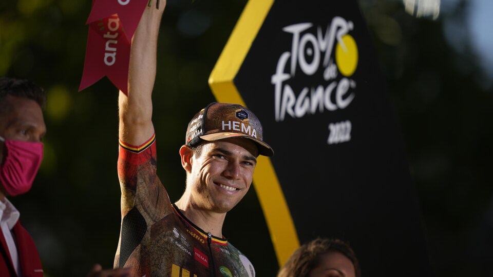 Wout van Aert soulève un bouquet de fleurs après son arrivée aux Champs-Élysées lors de la conclusion du Tour de France. 