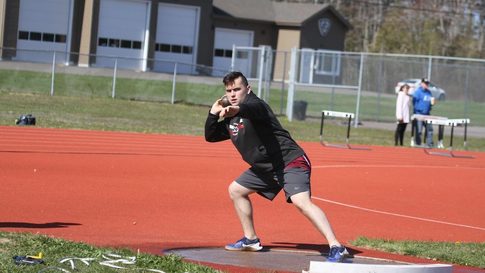Yanic en position de lancer un objet sur une piste d'athlétisme.