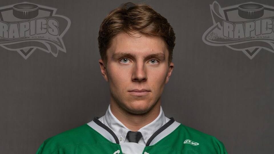 Joueur de hockey avec un chandail vert photographié devant un un fond gris