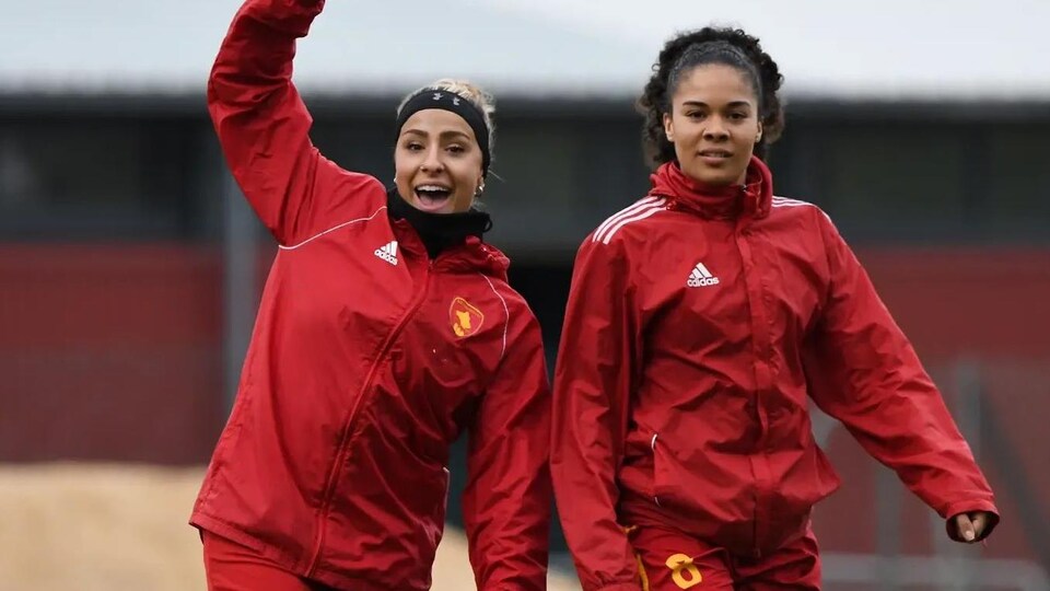 Yasmine Hall et Alexandria Lamontagne sur un terrain de soccer avec le manteau de leur équipe. 