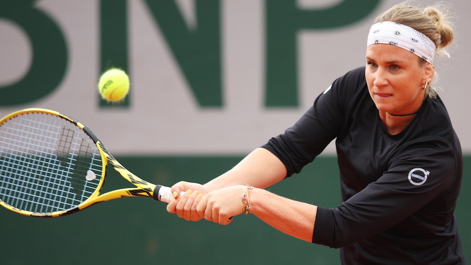 The tennis player hits the ball from the backhand.