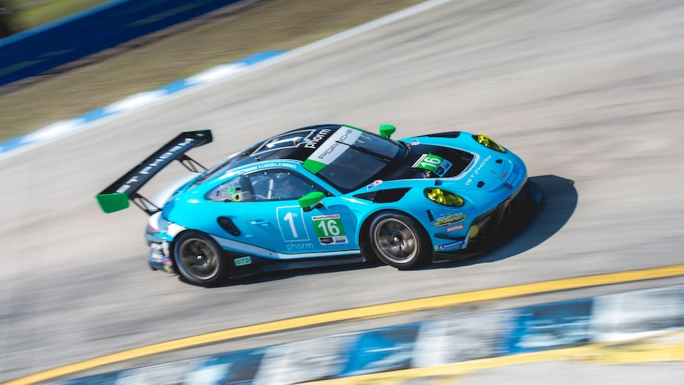 A blue car speeds up a race track.
