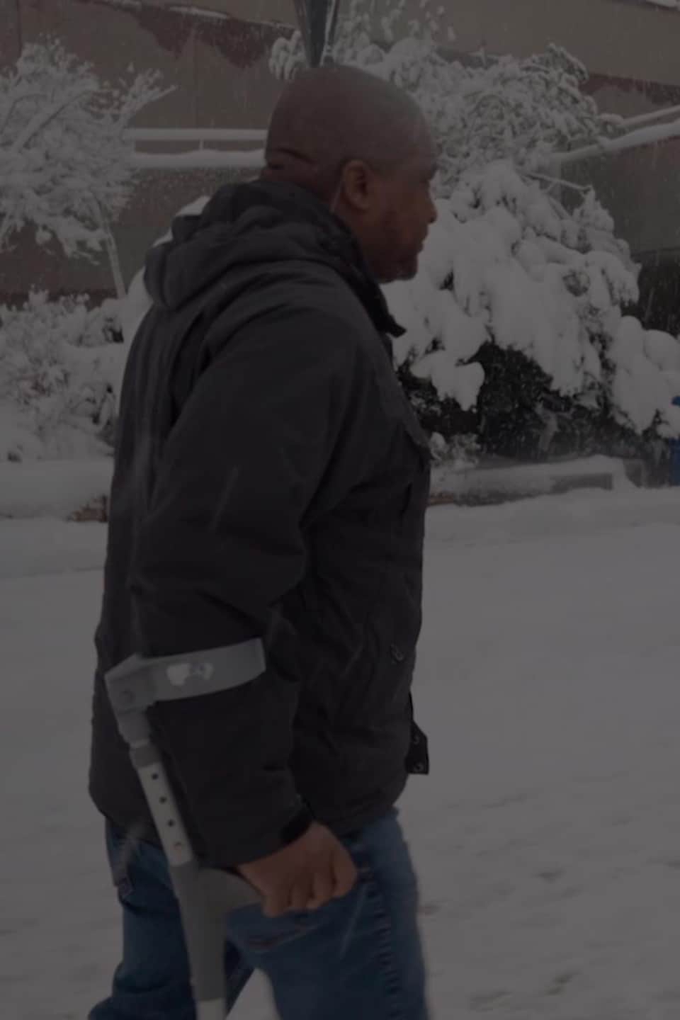 Un homme marche dans la neige, aidé d'une béquille