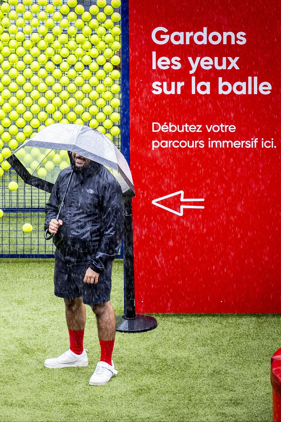 Un homme se cache sous son parapluie. À sa droite, une femme avec un imperméable