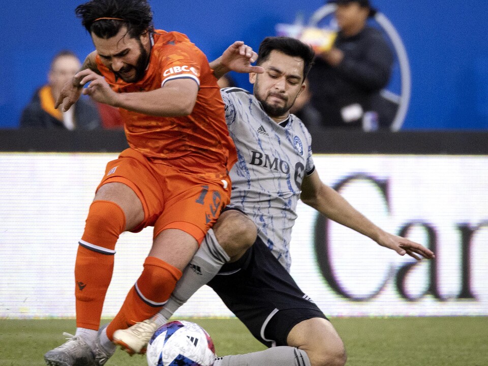 Un joueur tacle un autre joueur pour récupérer le ballon.