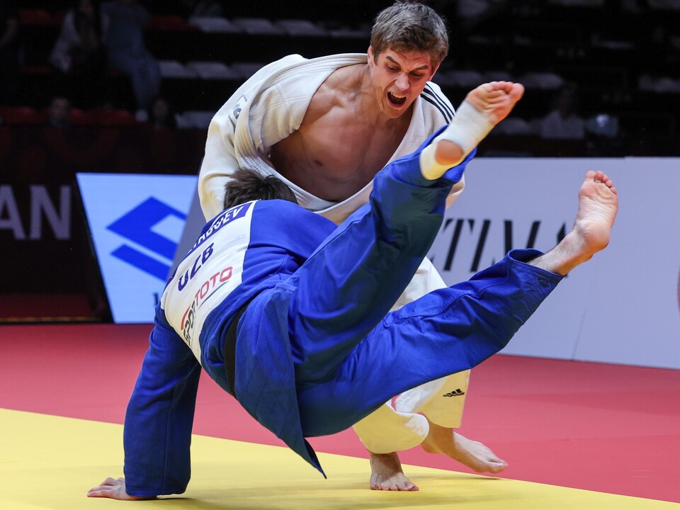 Un judoka crie et fait tomber son adversaire.